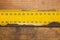 Old rusty yellow ruler with black numbers on a working wooden table. industrial background. carpentry workbench