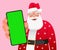 Old Santa Claus winks with a smartphone in his hand. Cute Santa shows a green phone screen to the camera in close-up. Place to