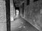Old and scary looking exterior hallway corridor next to an old building with dark and abandoned feeling to it in black and white