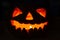 Old scary smiling glowing pumpkin lantern for halloween in the dark