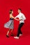 Old-school fashioned young couple dancing  on red background