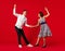 Old-school fashioned young couple dancing  on red background