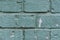Old scratched and dirty brick wall painted with aquamarine color
