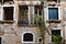 Old semi-destroyed building and crooked windows with rusted metal bars in Venice, Italy