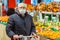 Old senior european man wearing protective facial mask pushing shopping cart in the supermarket. Shopping during COVID-19 concept