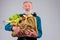 Old senior grandfather holding cotton reusable shopper bag full of natural farmer vegetables:corn,bananas grapes