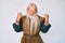 Old senior man with grey hair and long beard wearing viking traditional costume very happy and excited doing winner gesture with