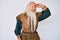 Old senior man with grey hair and long beard wearing viking traditional costume very happy and smiling looking far away with hand