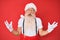 Old senior man with grey hair and long beard wearing white t-shirt and santa claus costume crazy and mad shouting and yelling with