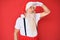 Old senior man with grey hair and long beard wearing white t-shirt and santa claus costume very happy and smiling looking far away