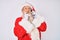 Old senior man wearing santa claus costume speaking on the phone serious face thinking about question with hand on chin,