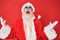 Old senior man wearing santa claus costume and sunglasses crazy and mad shouting and yelling with aggressive expression and arms