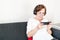 Old senior woman female sit home flat couch hold smartphone play game happy headphones alone relax enjoy