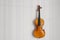 Old shabby broken yellow violin for restoration hanging on the wall with copy space for your text