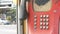 Old shabby red telephone set on a city street. Vintage telephone in the phone booth