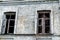 Old shabby ruined abandoned brick building wall facade with two wooden brocken glass windows and dark black background