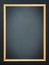Old shabby stained blank chalkboard in a wooden border on a dark wall. Vertical photo