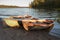 Old shabby wooden fishing colorful boats on the lake shore during sunset, autumn forest on background