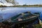 Old shabby worn wooden boats, painted green at river bank in shade of willow tree, late summer morning landscape