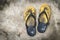 Old and shabby yellow flip-flops lay on the concrete floor