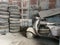 In the old shed, there are broken old motorbikes left behind,  and many old truck tires. Rusty old galvanized shed wall.