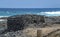 Old simple stone bunker house on the rocky beach with waves at daytime in summer