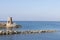 Old small lighthouse and stone wave breakers of Recco on a sunny summer day.