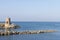 Old small lighthouse and stone wave breakers of Recco on a sunny summer day. Coast of Italy