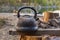 Old smoked kettle is on a wooden bench on a picnic street