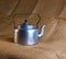 An old soldier\\\'s aluminum teapot from the Second World War against the background of burlap