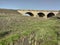 Old soviet bridge. Little gray river. Green grass.