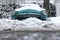 Old Soviet car Volga. Turquoise retro car covered with snow. GAZ-21 on the street