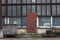 Old soviet constructivist industrial building exterior facade with red steel door, large windows, blue glass bricks. Rusty, trolly