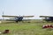 An old Soviet-era plane stands on a field airfield among barrels of fuel