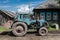 Old Soviet Tractor Next to a Wooden House in Poor village of Bolshoy Balchug in Siberia