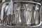 Old spoon, forks, knives on a metal tray and sold at a flea market, top view