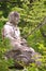 An old statue of a seated Buddha surrounded by trees