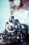 Old steam locomotive against blue cloudy sky, vintage train