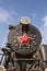 An old steam locomotive with red wheels and a red star stands in an open-air Museum on the seaside Boulevard embankment in Baku, A