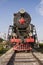 An old steam locomotive with red wheels and a red star stands in an open-air Museum on the seaside Boulevard embankment in Baku, A