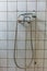 Old steel shower faucet at white vintage tile background