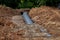 An old steel water pipe with a welded flange lies next to a new plastic pipe installed to connect the water