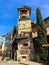 Old stone ancient carved beautiful antique European clock tower with dial on the background of the blue sky and the tourist city.