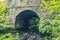 An old stone bridge in the Irish countryside with a tiny river running underneath