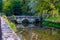 Old stone bridge over river Coln at Bibury village in Cotswold, Gloucestershire, England, UK