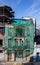 Old stone building uninhabited and in ruins, covered by a green cloth. Galician city of Lugo, Spain