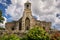 An old stone church with a simple tower with a bell.