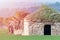 Old stone farmer`s hut with sun glare on one side in a green field