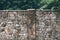 Old stone fence and green deciduous plants behind