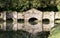 Old stone footbridge reflected in river